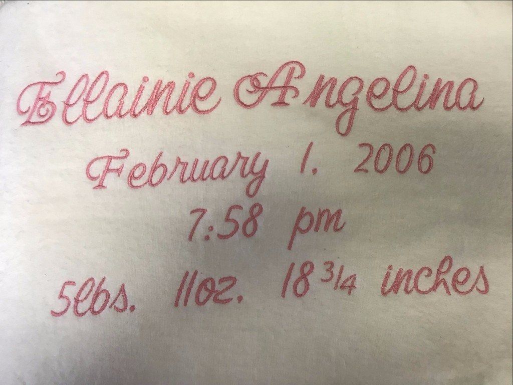 Embroidered red text on fabric: Ellainie Angelina, February 1, 2006, 7:58 pm, 5 lbs. 11 oz., 18 3/4 inches.