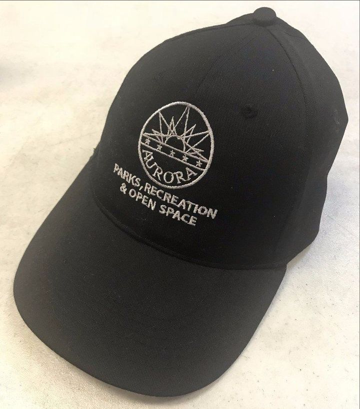 A black baseball cap featuring the white embroidered logo of the Aurora Parks, Recreation & Open Space department.