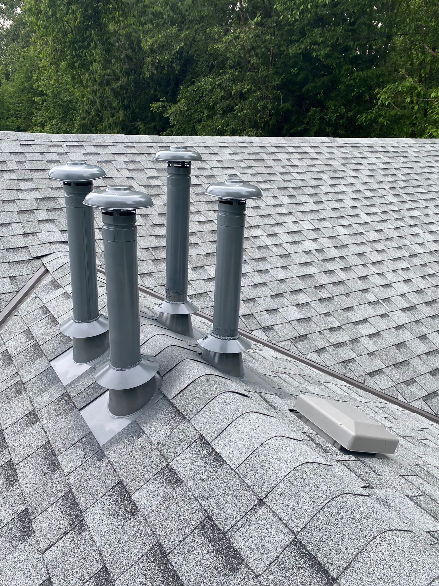 There are three chimneys on the residential roof of a house.