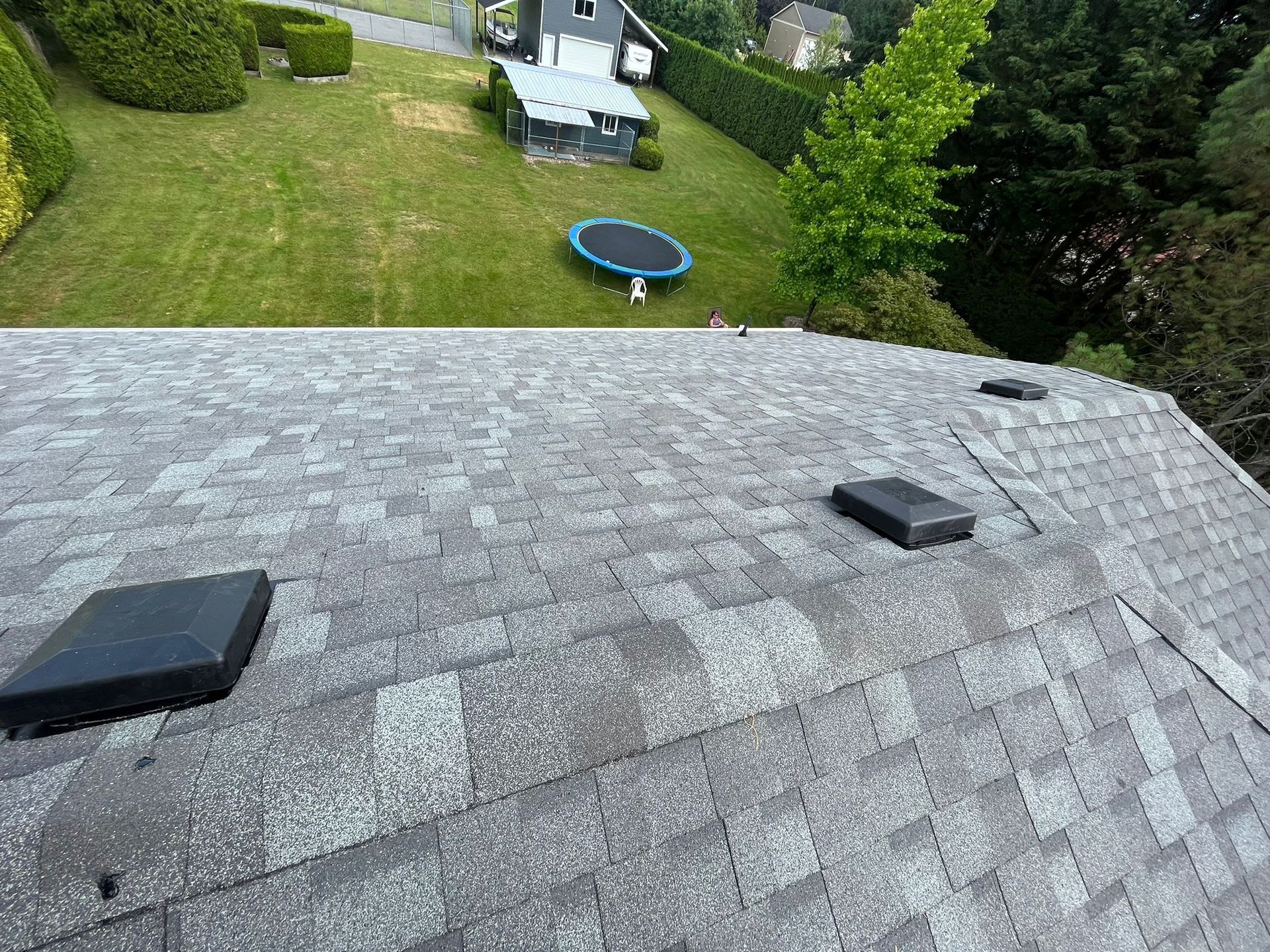 A trampoline is sitting on the roof of a house.
