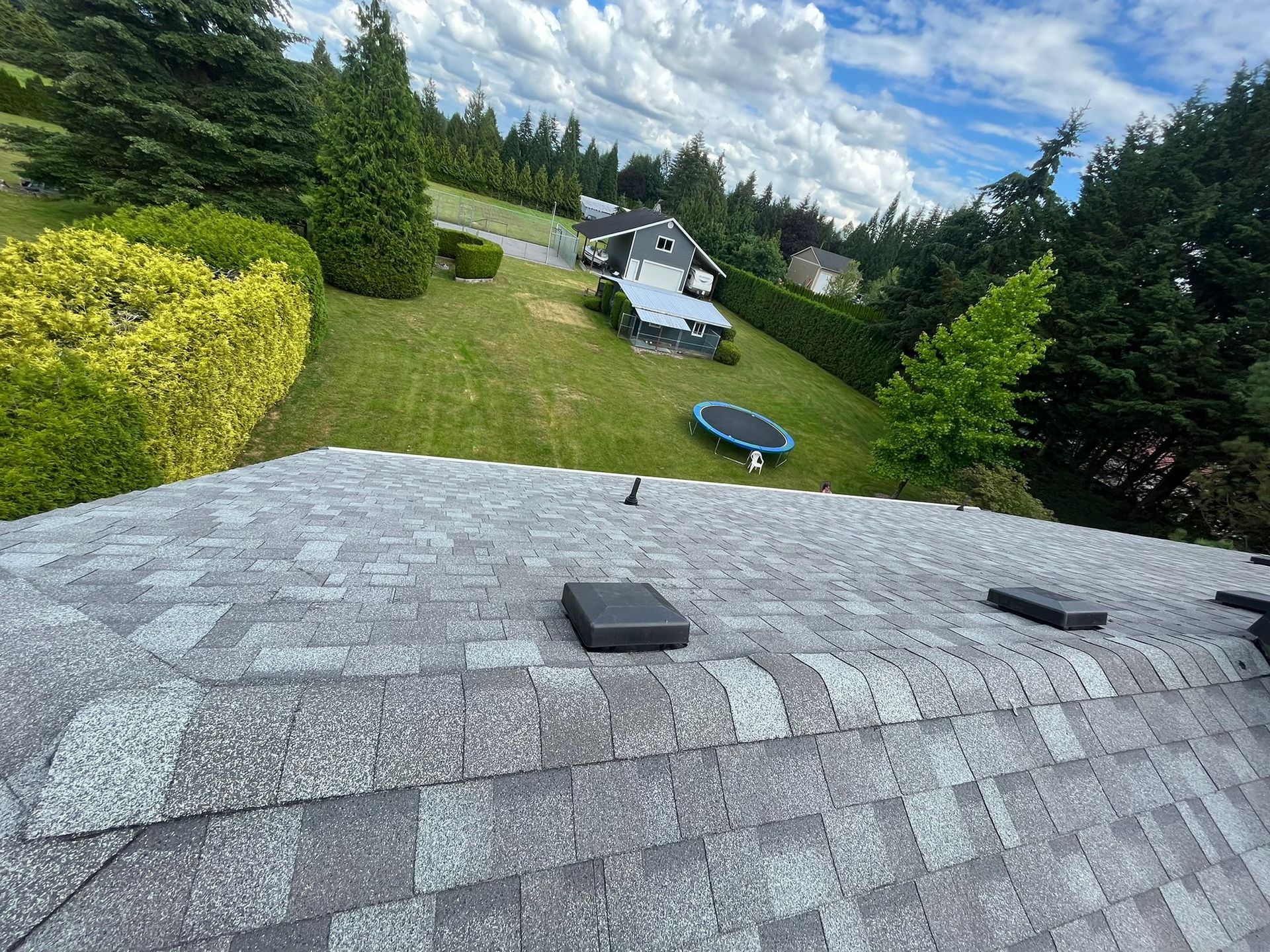 The roof of a house with a trampoline in the backyard.