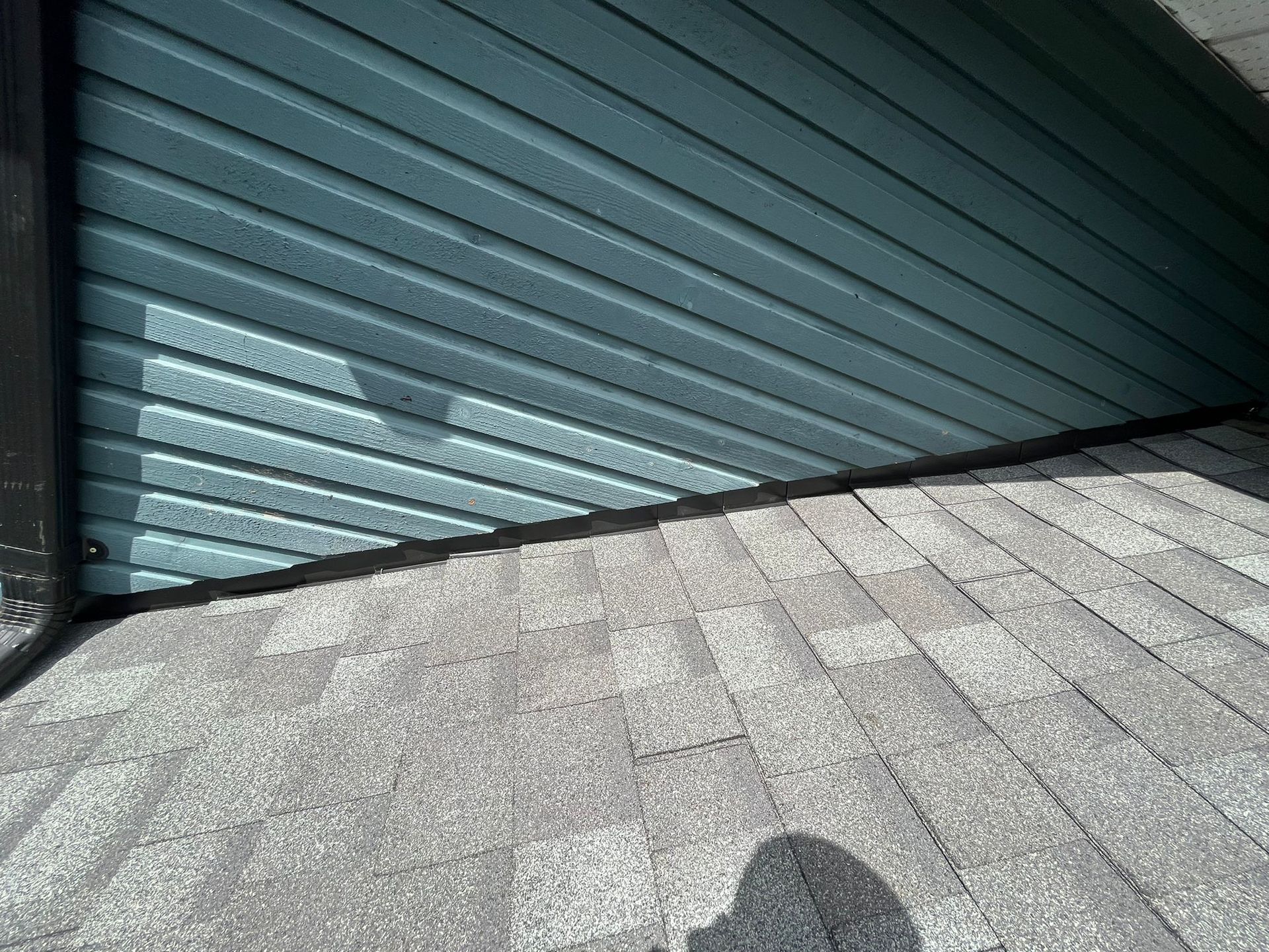A close up of a garage door with a shadow on the ground.