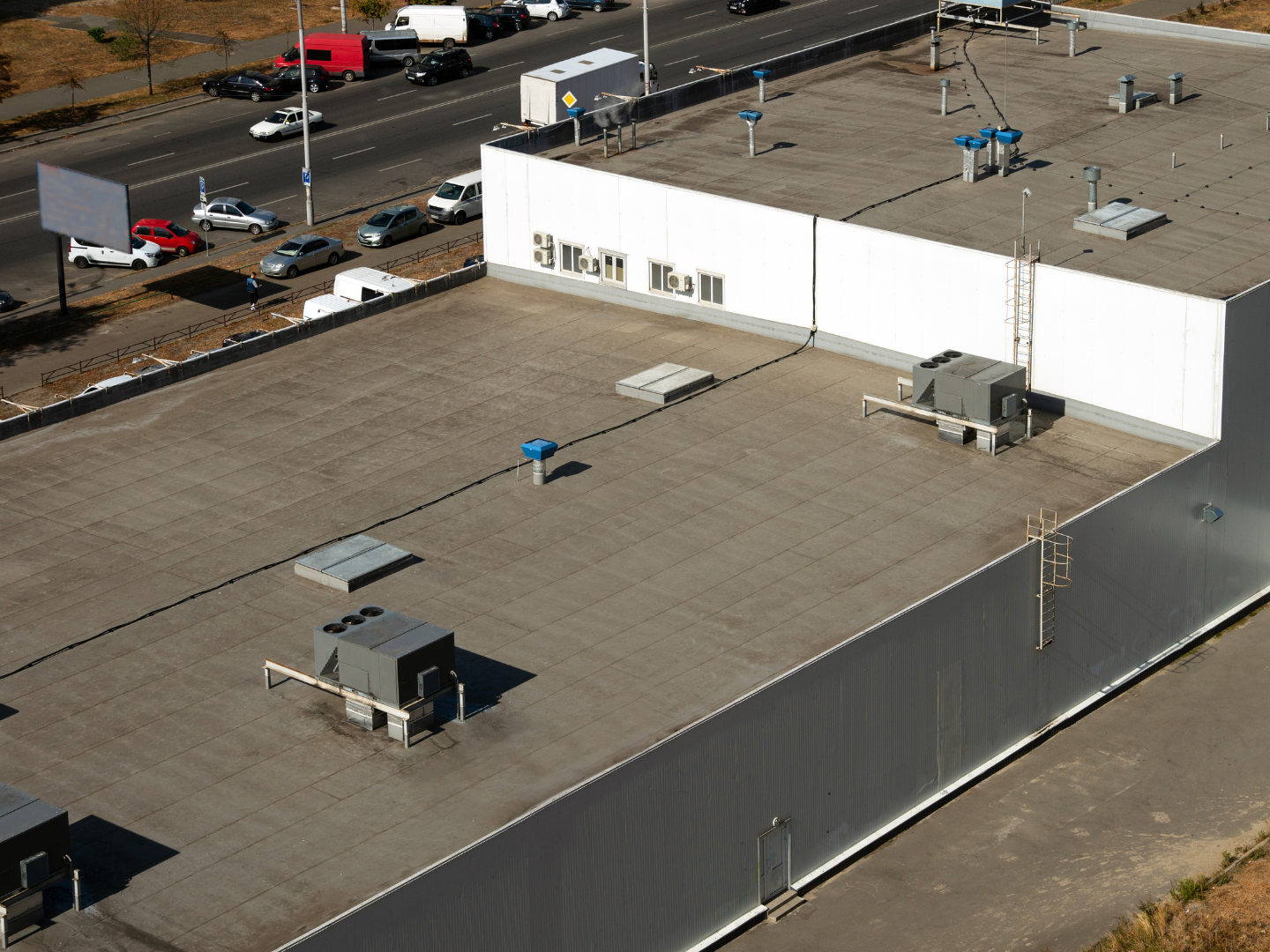 A roof with a vent on it and a building in the background.
