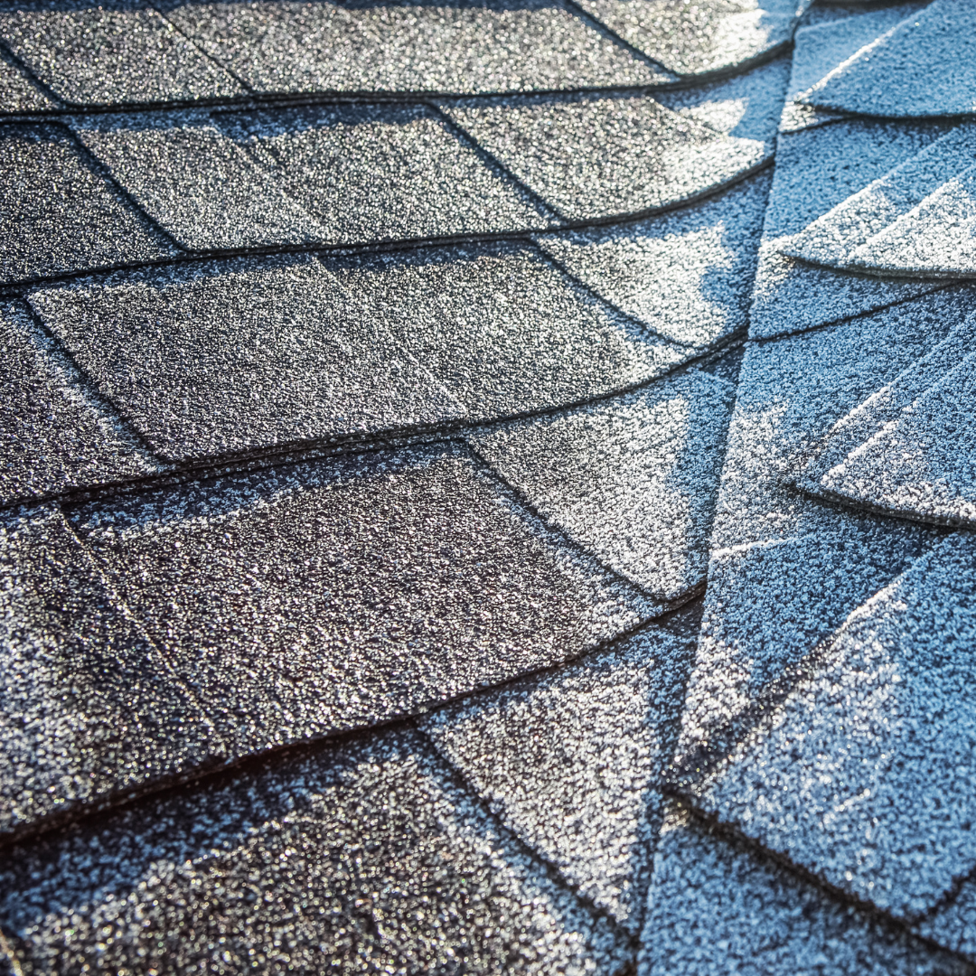 Close-up of a weathered cedar shake roof under a clear blue sky with a dome skylight.