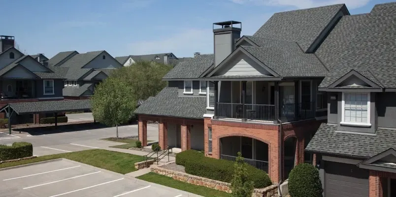 A roof with a vent on it and a building in the background.