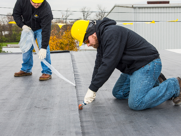 A roof with a vent on it and a building in the background.
