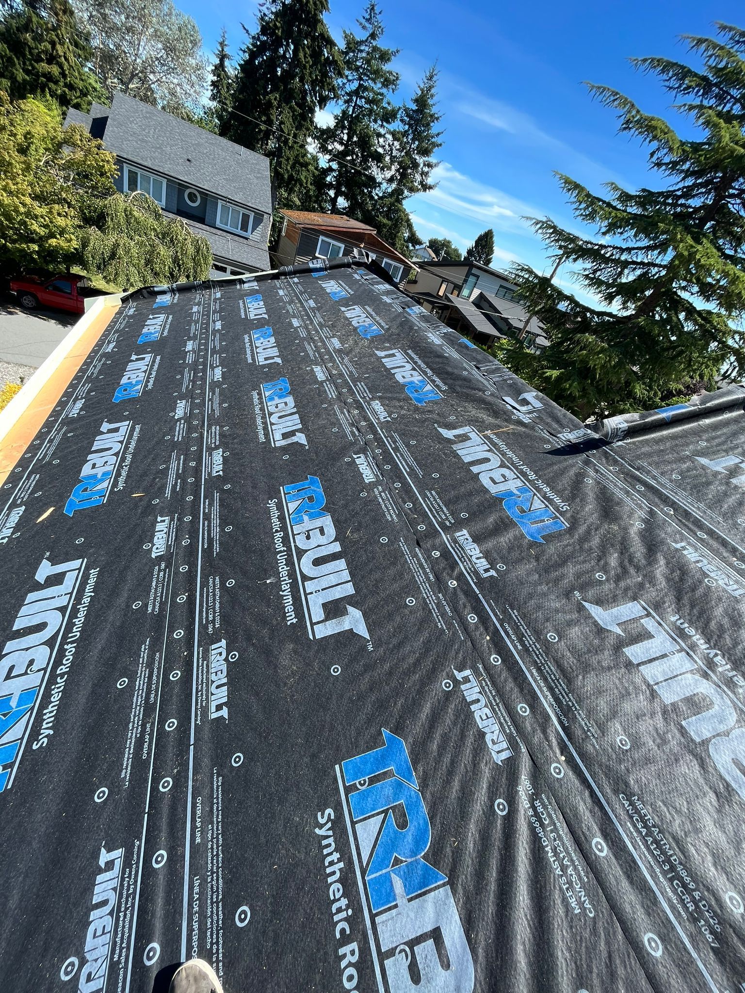 A roof with a vent on it and a building in the background.