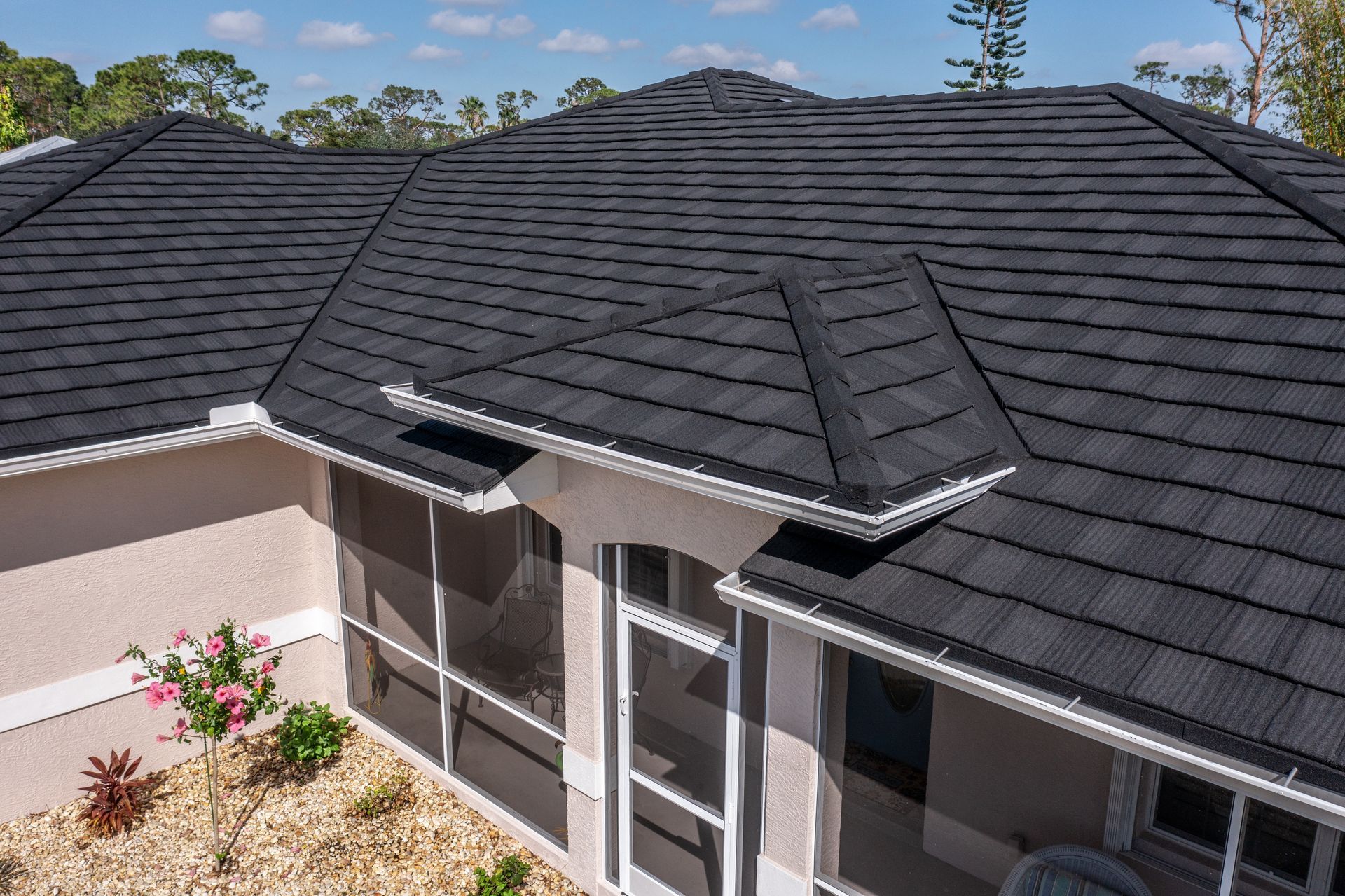 A roof with a vent on it and a building in the background.
