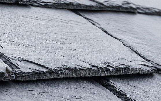 A roof with a vent on it and a building in the background.