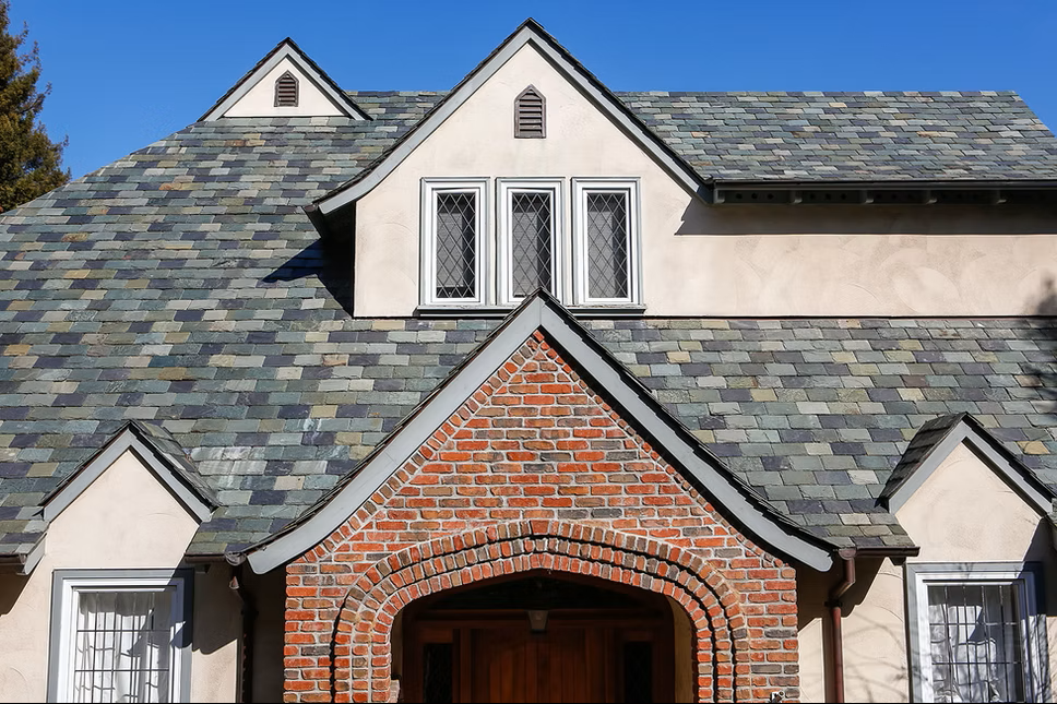 A roof with a vent on it and a building in the background.