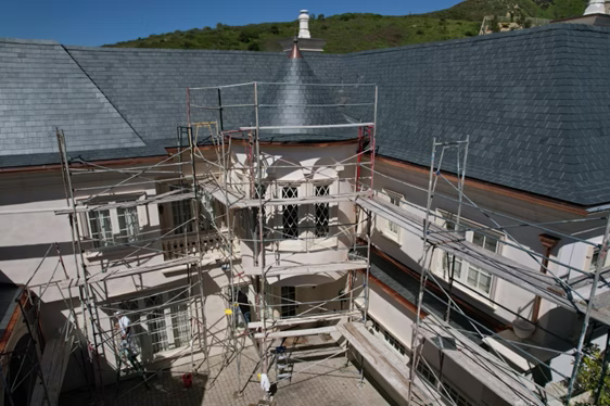 A roof with a vent on it and a building in the background.