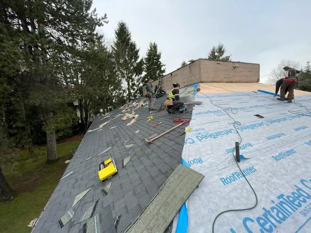 A group of people are working on the roof of a house.