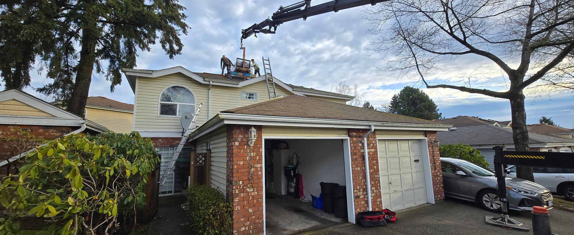 A crane is lifting a roof of a house.