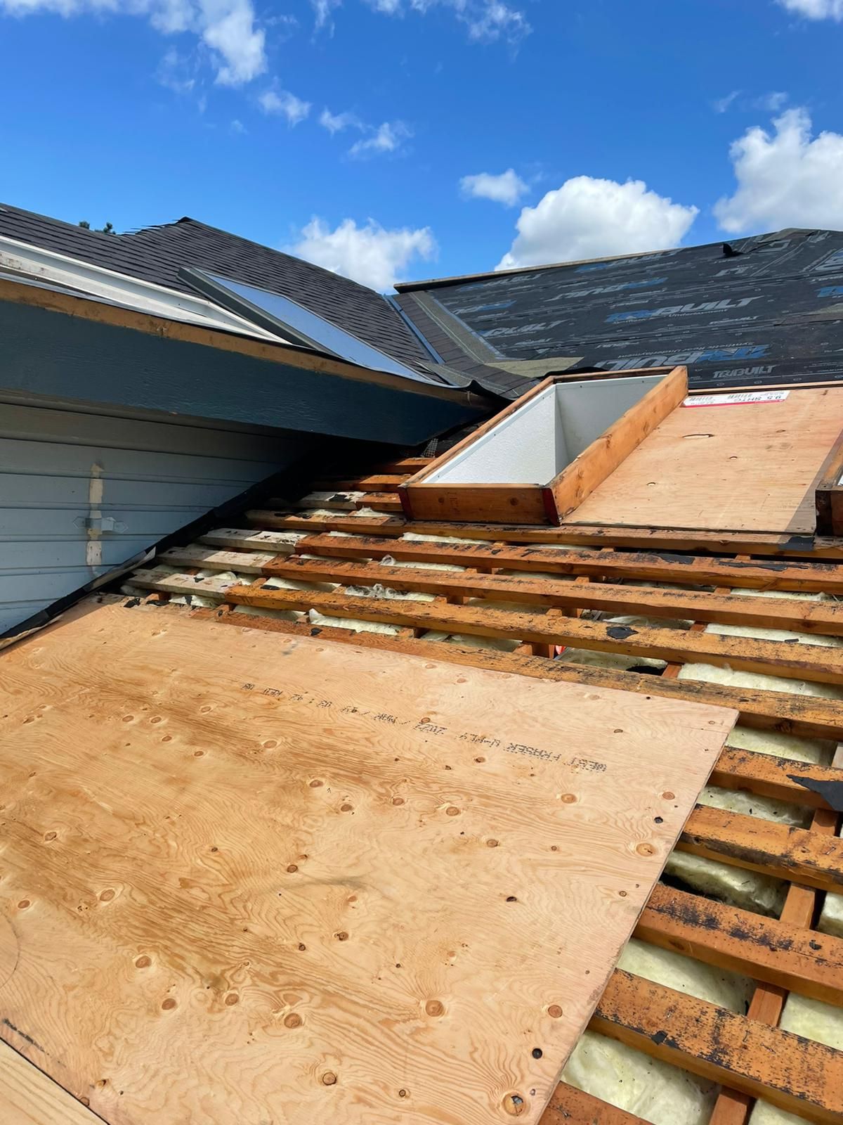 The roof of a house is being remodeled with wooden beams and shingles.