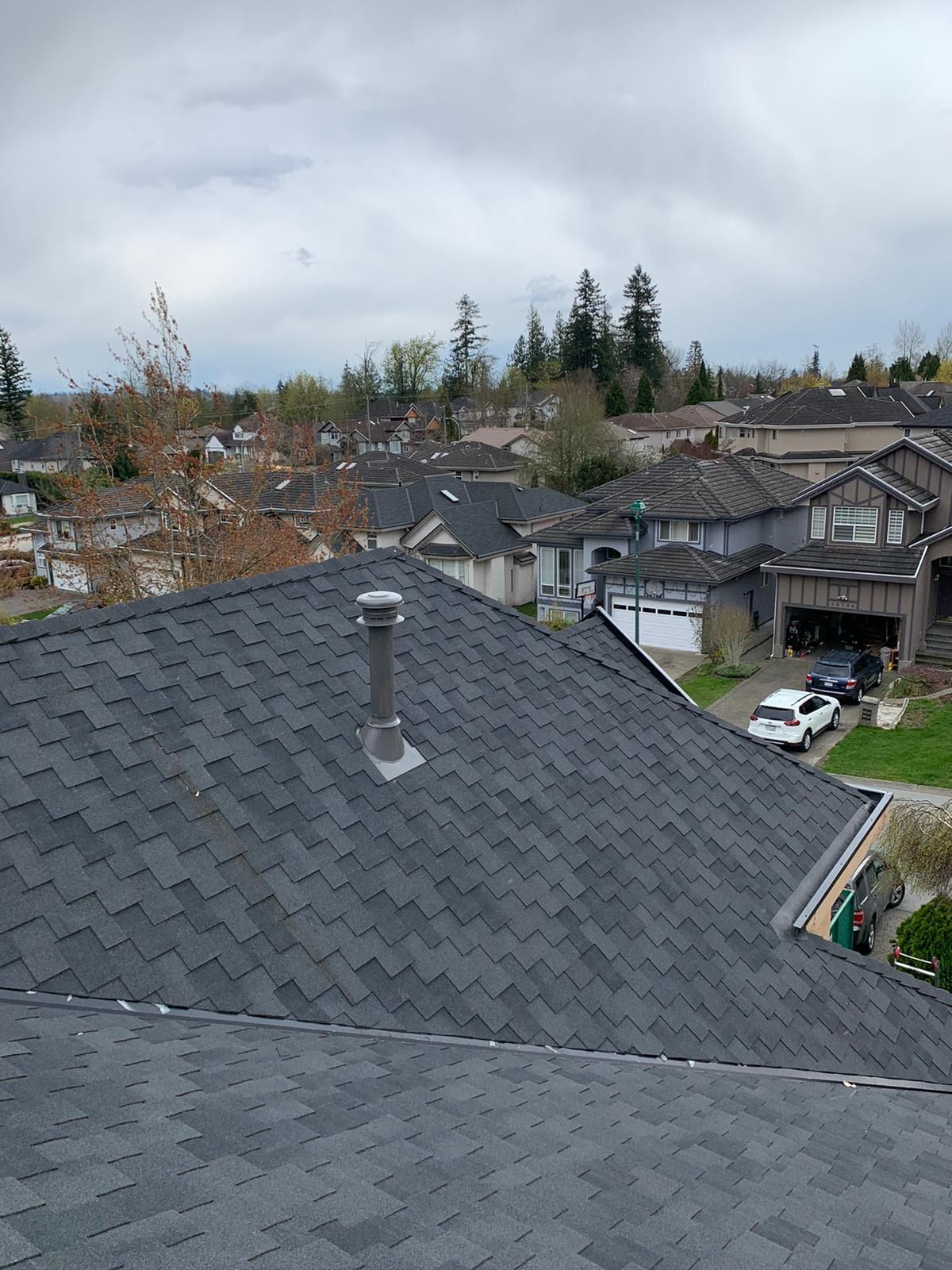 A roof with a chimney on it is surrounded by houses in a residential area.