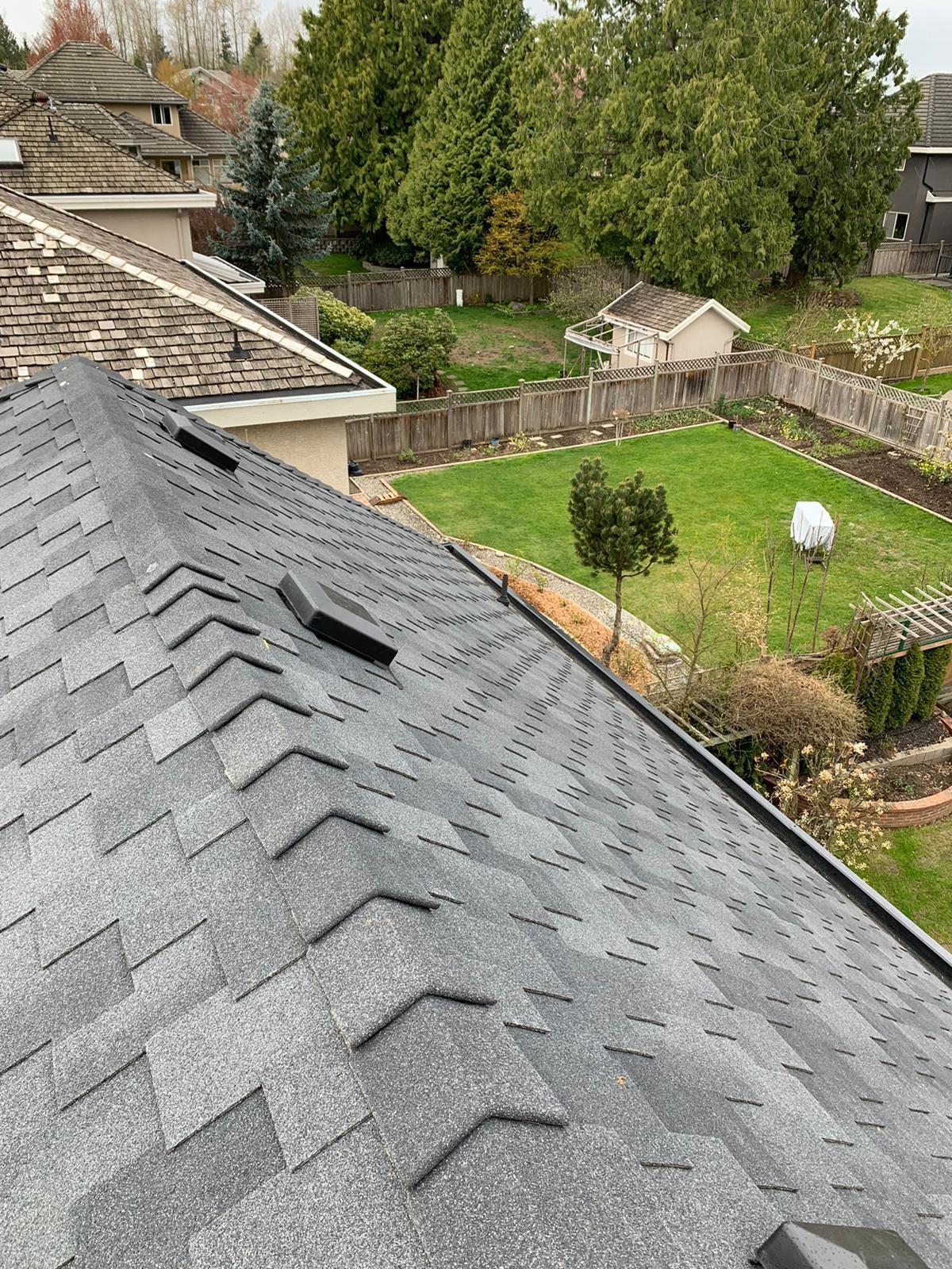 A roof with a lot of shingles on it and a fence in the background.