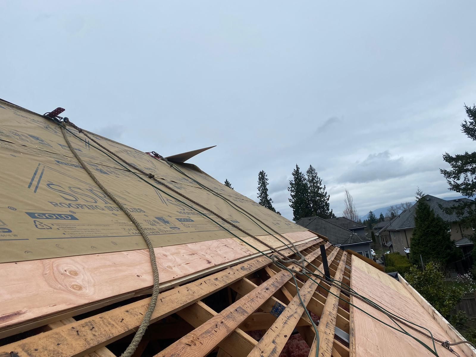 A roof is being built with a lot of wood and ropes.