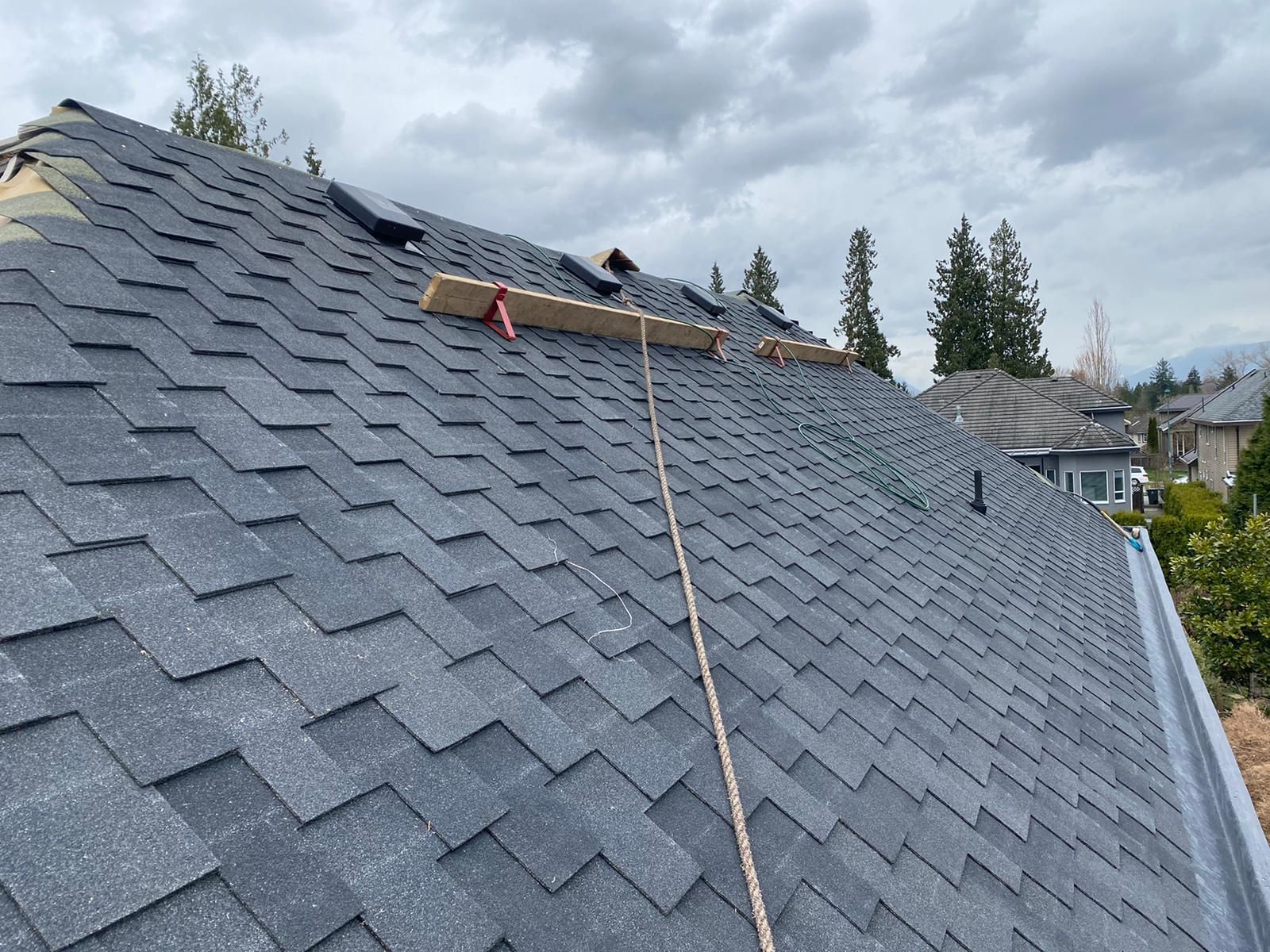 A roof with shingles being installed and a rope attached to it.