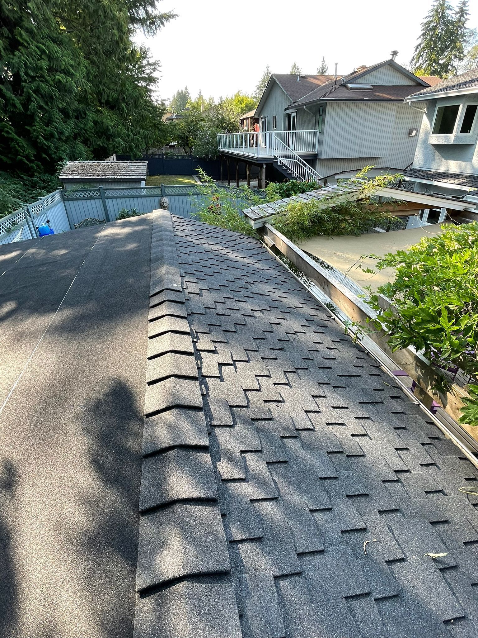 A roof with a lot of shingles on it and a house in the background.