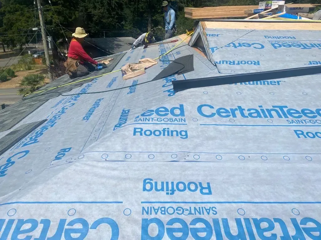 A man is working on a roof with certainteer roofing paper