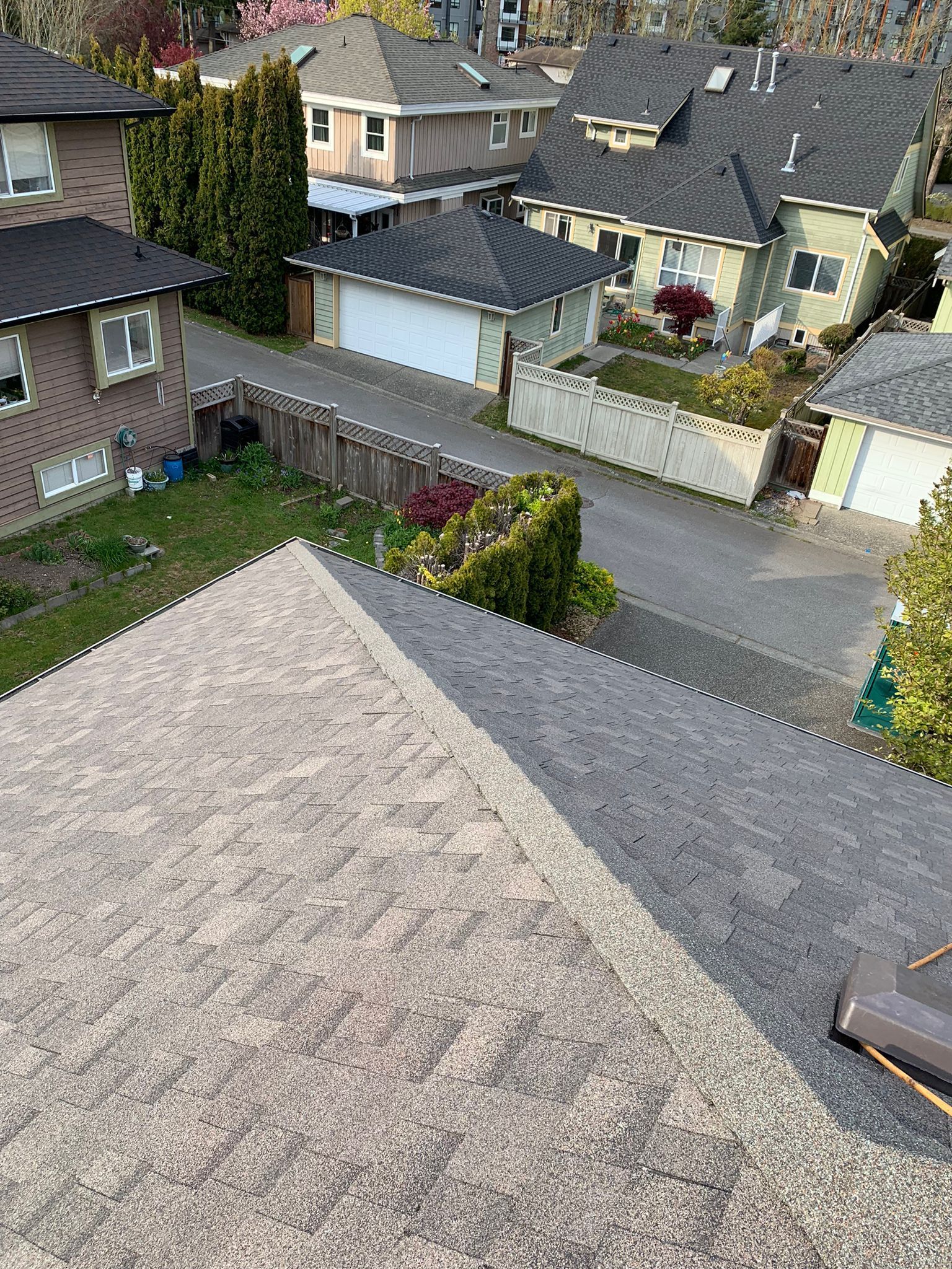 An aerial view of a residential neighborhood with a roof in the foreground.