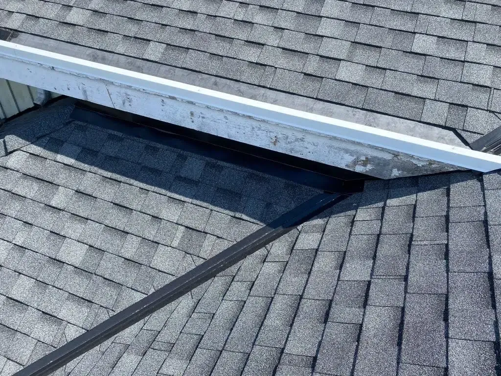 A close up of a roof with shingles and a white gutter.