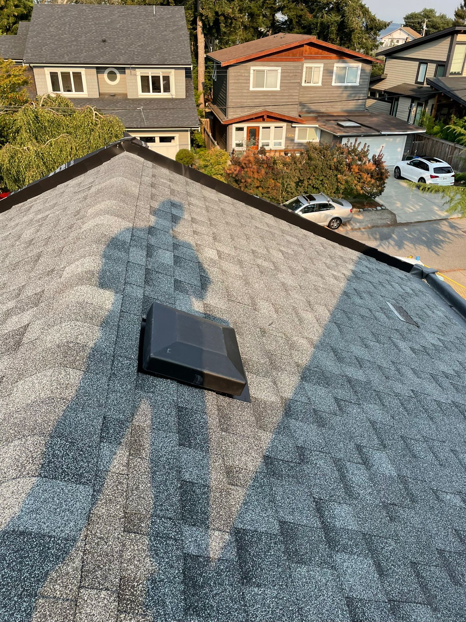 A shadow of a person is cast on the roof of a house.