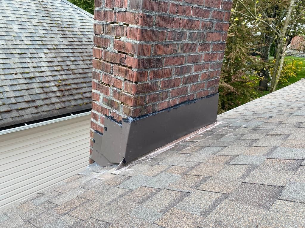A brick chimney is on the roof of a house.