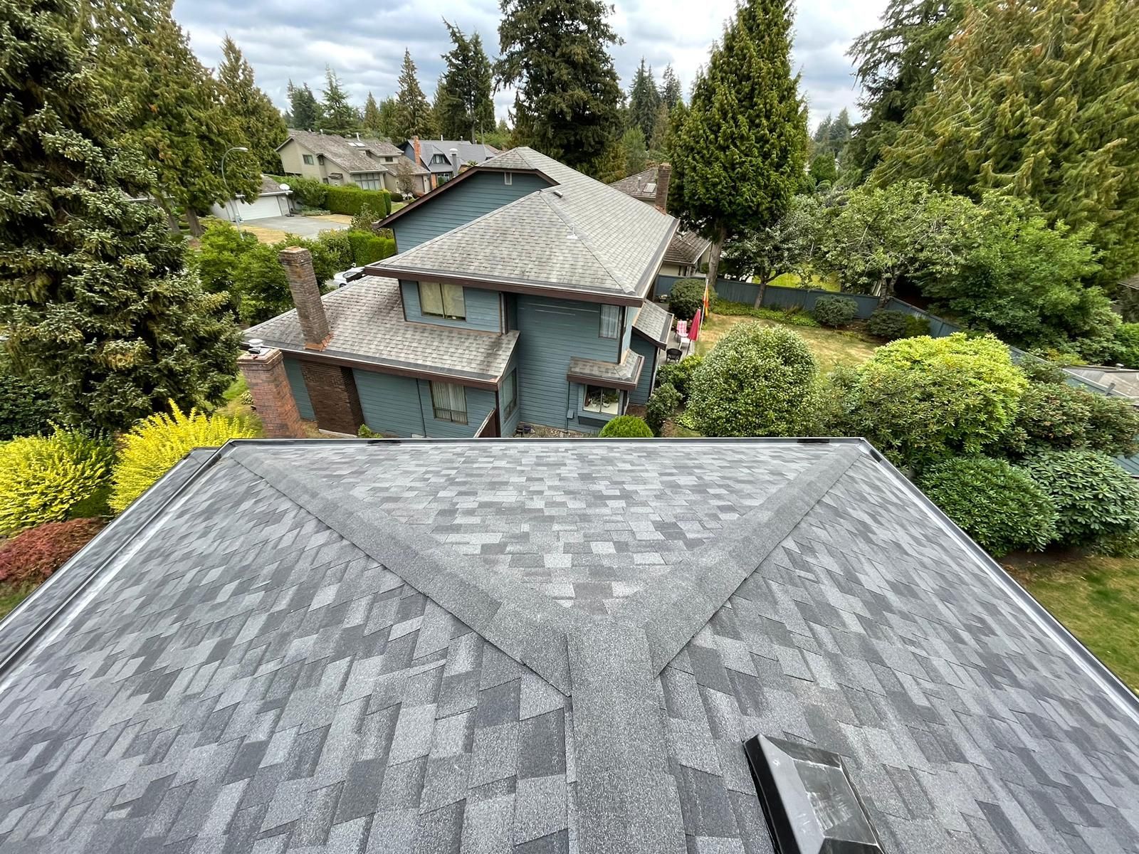 An aerial view of a roof of a house with trees in the background.