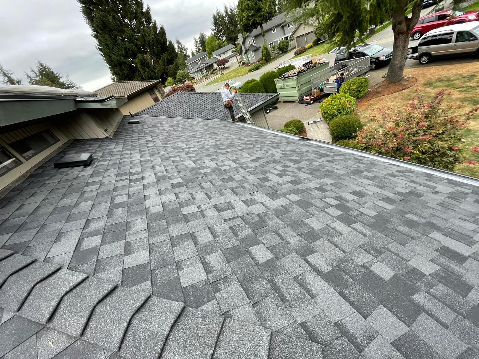 vancouver roofer is standing on the roof of a house with asphalt shingles.