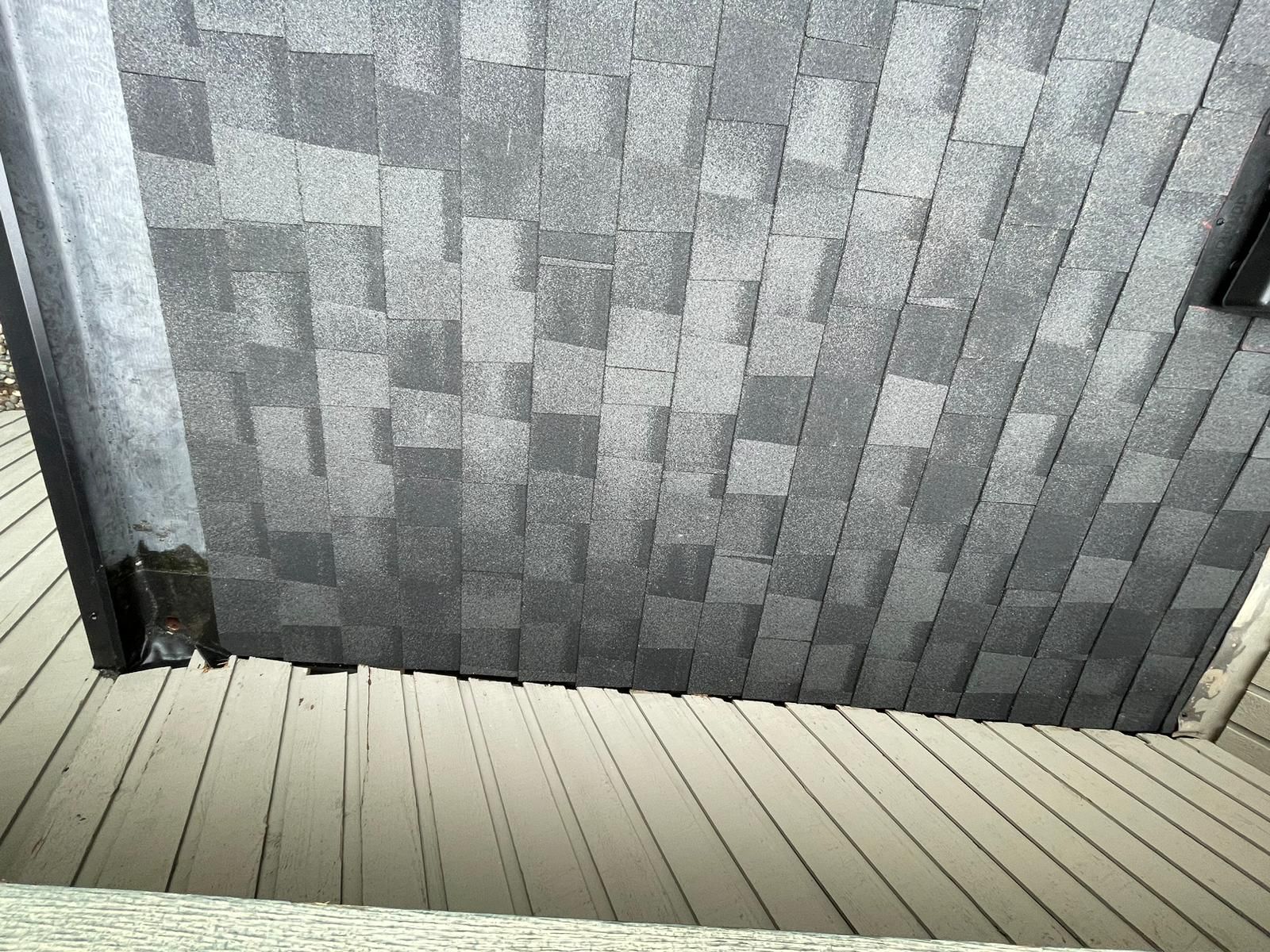 A roof with a lot of shingles on it is sitting on top of a wooden deck.