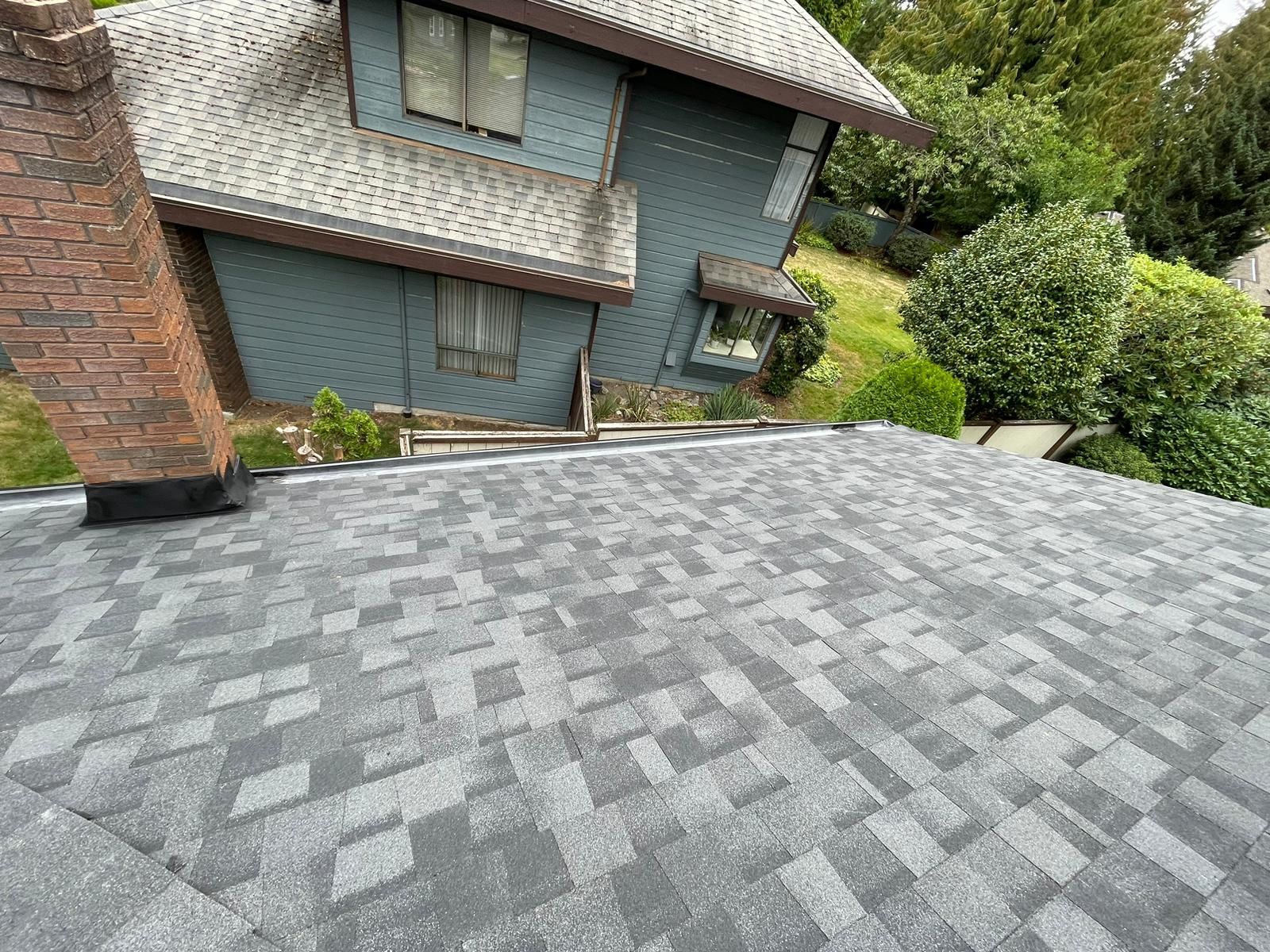 A house with a gray roof and a chimney on the side of it.