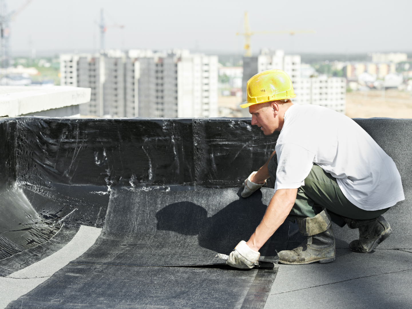 A roof with a vent on it and a building in the background.