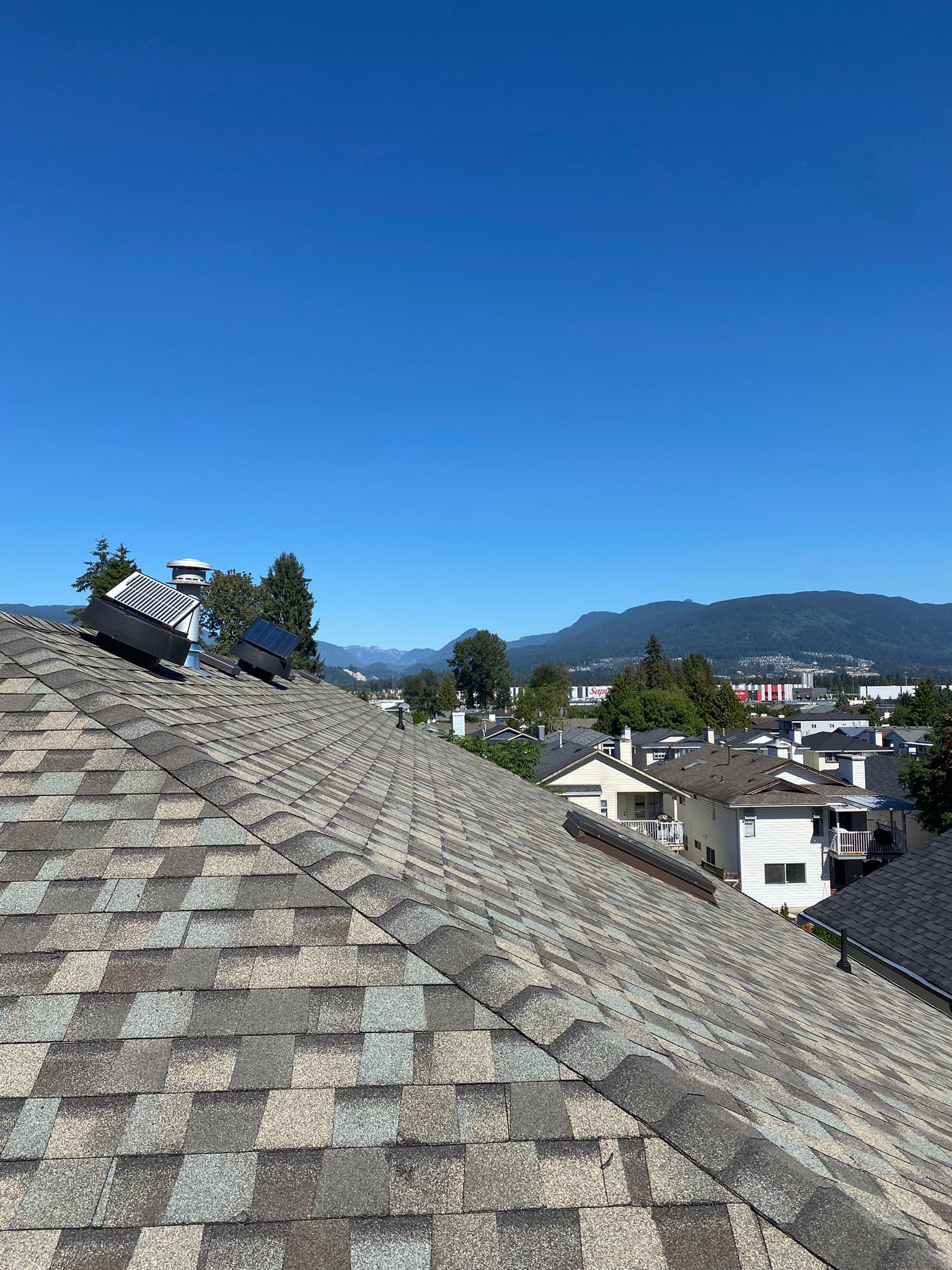 A roof with a view of a city and mountains in the background.