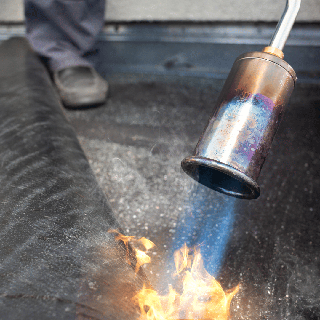 A person is using a torch to ignite a fire on a roof. torch on roofing, vancouver roofing