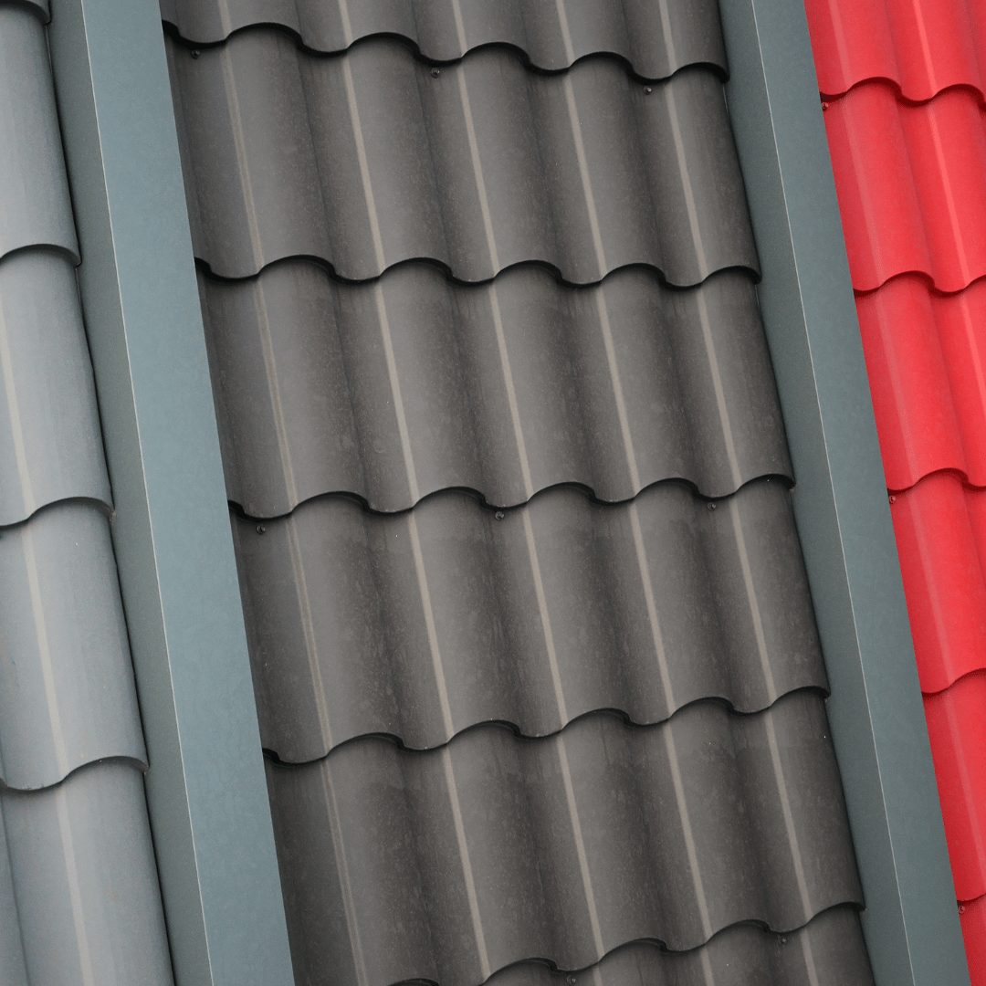 Close-up of three corrugated metal roof tiles in gray, charcoal, and red.