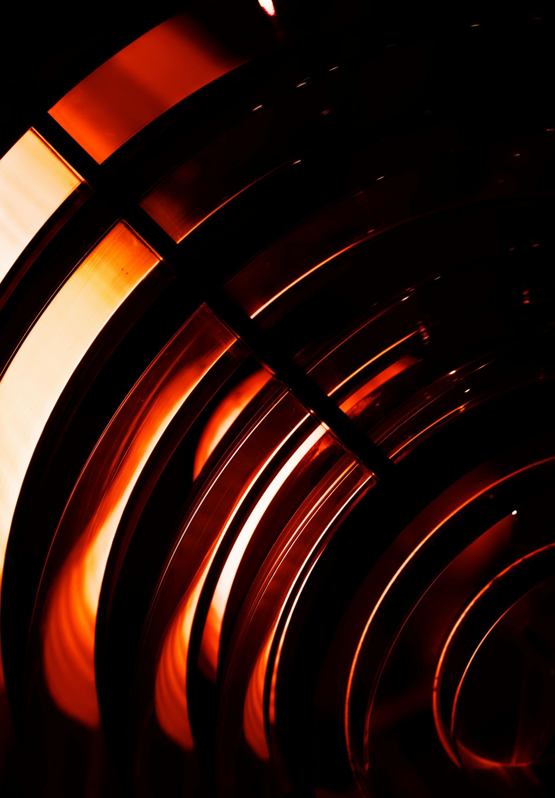 Abstract shot of glowing orange curved bands in a dark space.