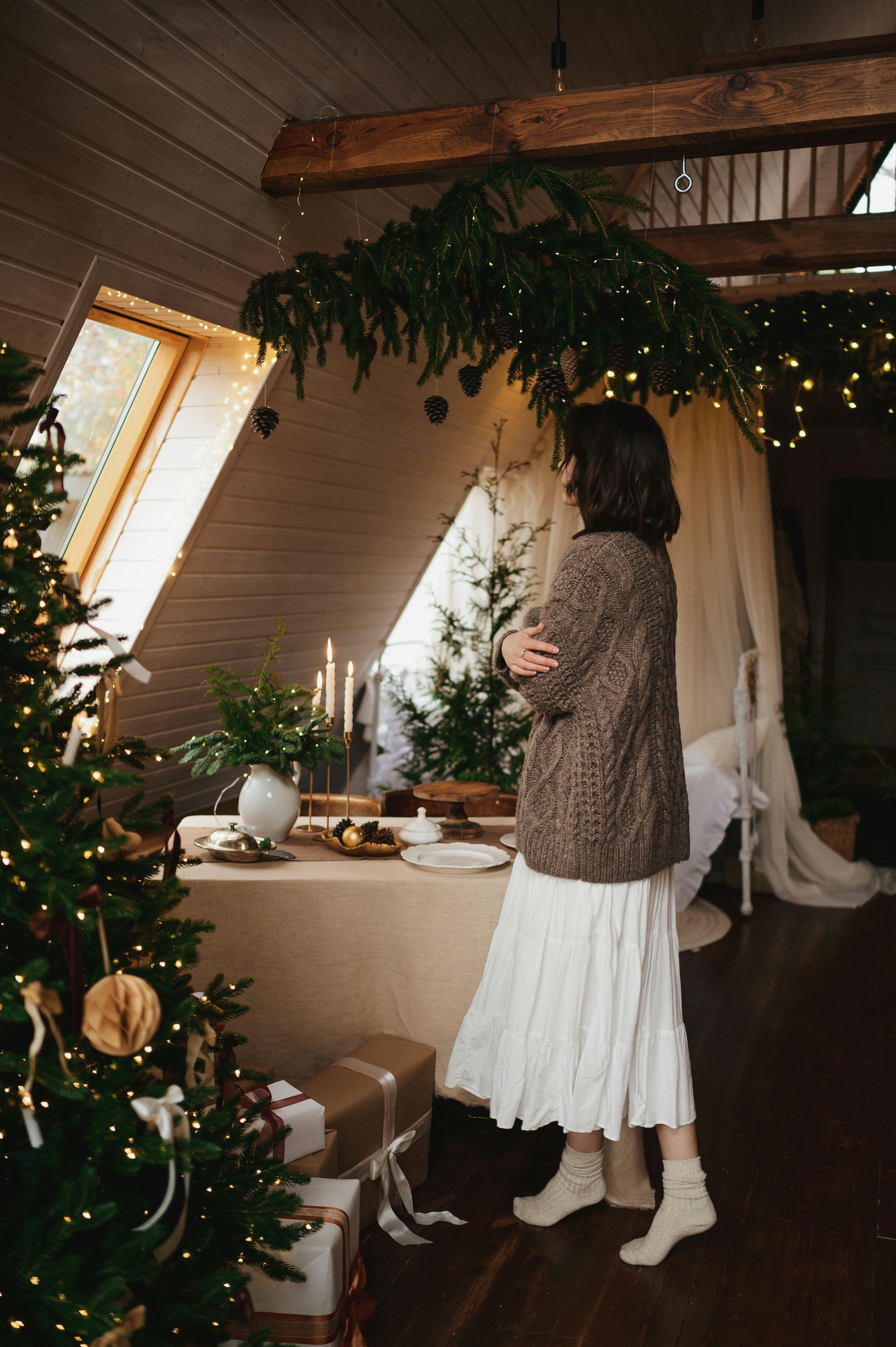 A woman is standing in front of a christmas tree in a room.