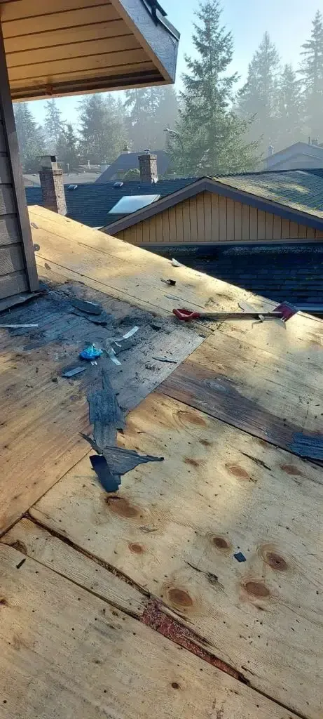 A wooden deck with a screwdriver on it and a roof in the background.