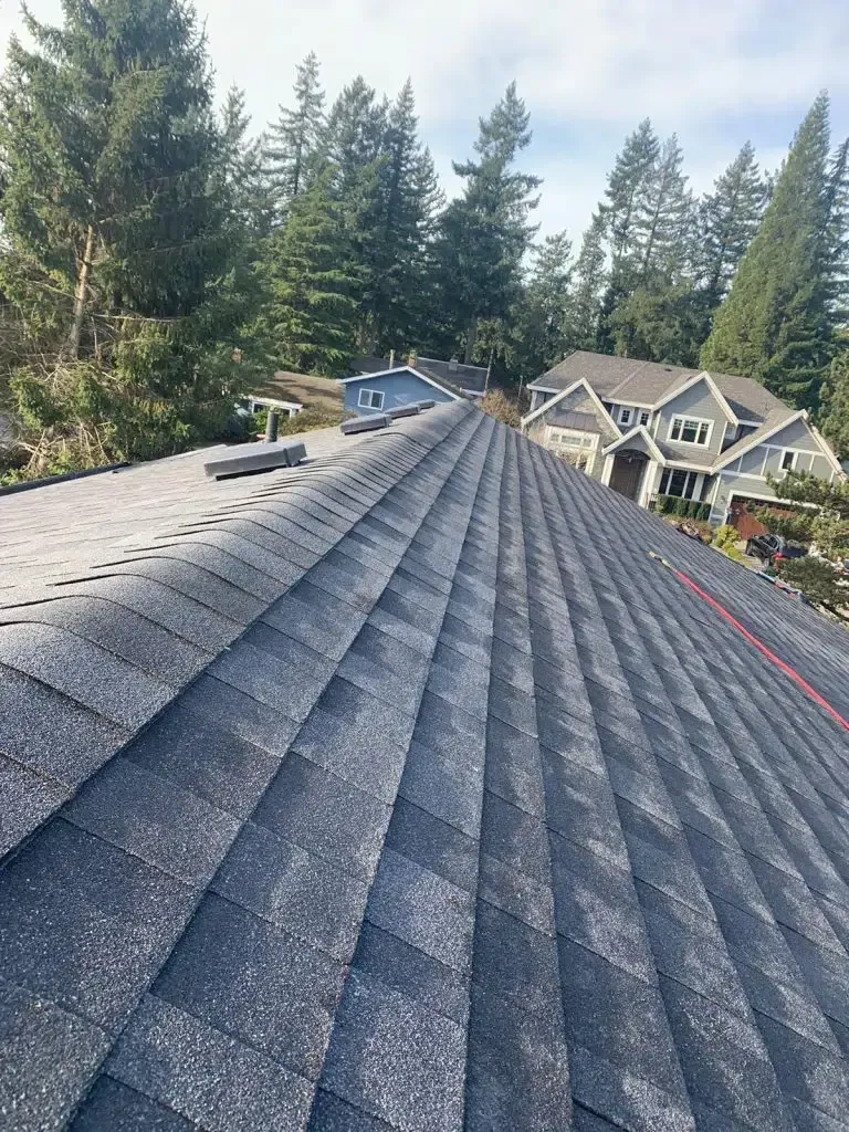 A roof with a lot of shingles on it and a house in the background.