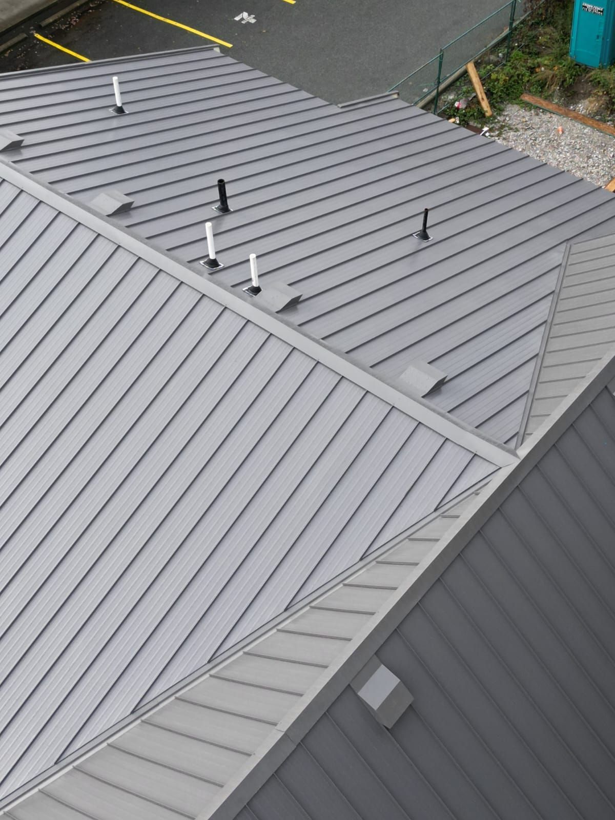 A roof with a vent on it and a building in the background.