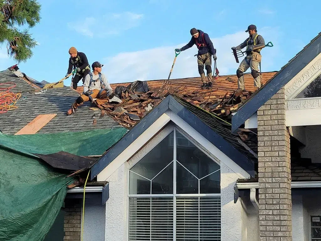 A group of men are working on the roof of a house.