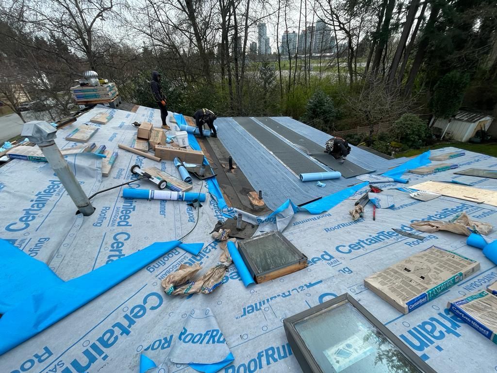 A roof is being installed on a house with a surrey bc in the background.