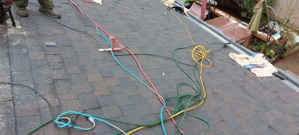 A person is working on a roof with ropes and wires.