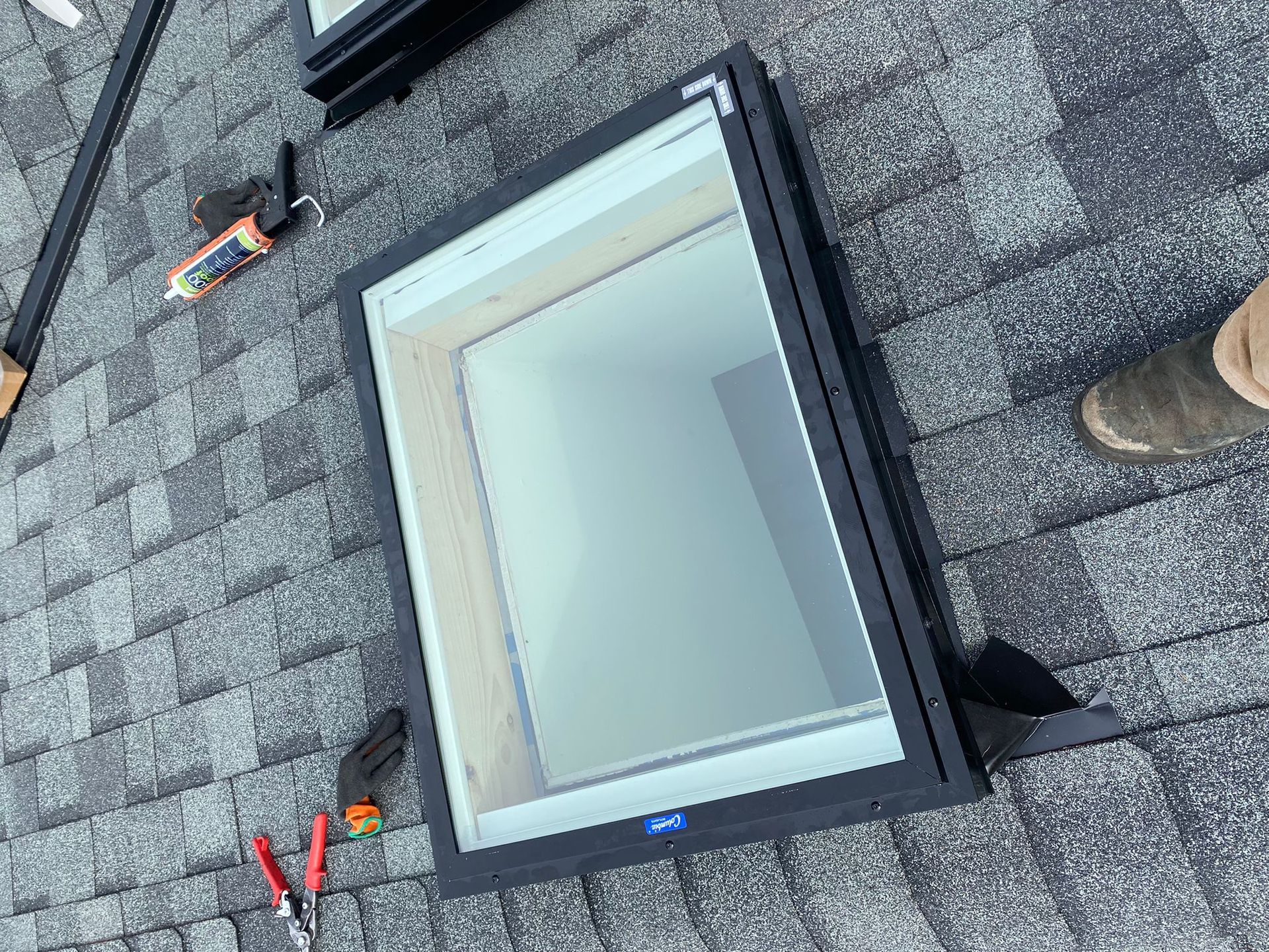 A man is installing a skylight on a roof.
