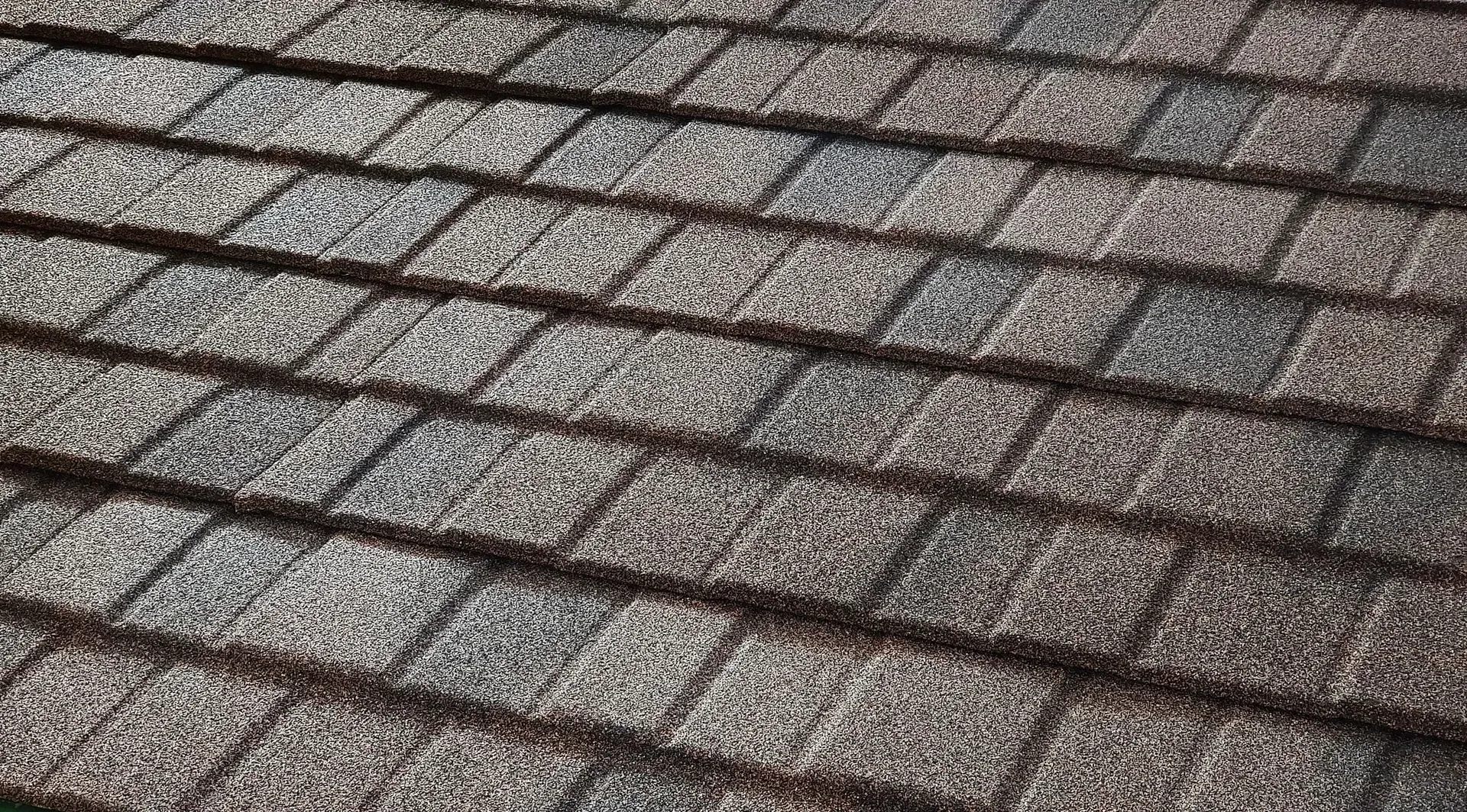 A roof with a vent on it and a building in the background.