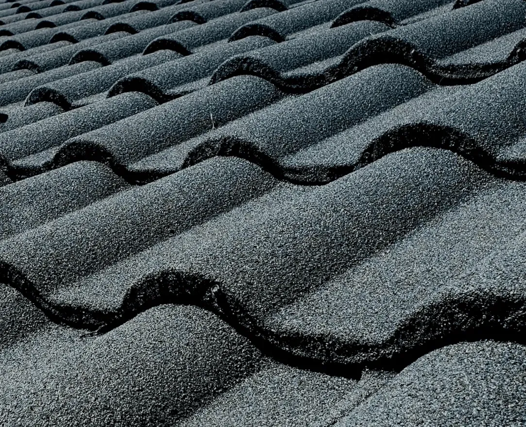 A roof with a vent on it and a building in the background.