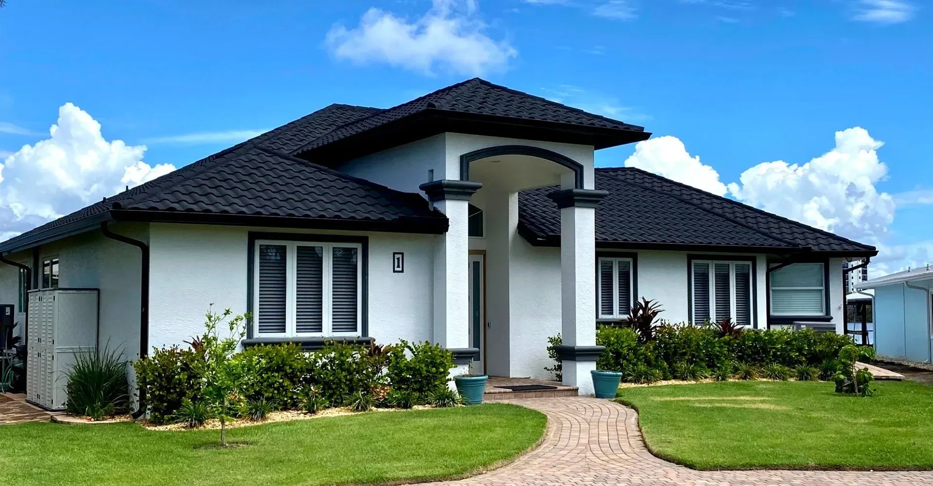 A roof with a vent on it and a building in the background.
