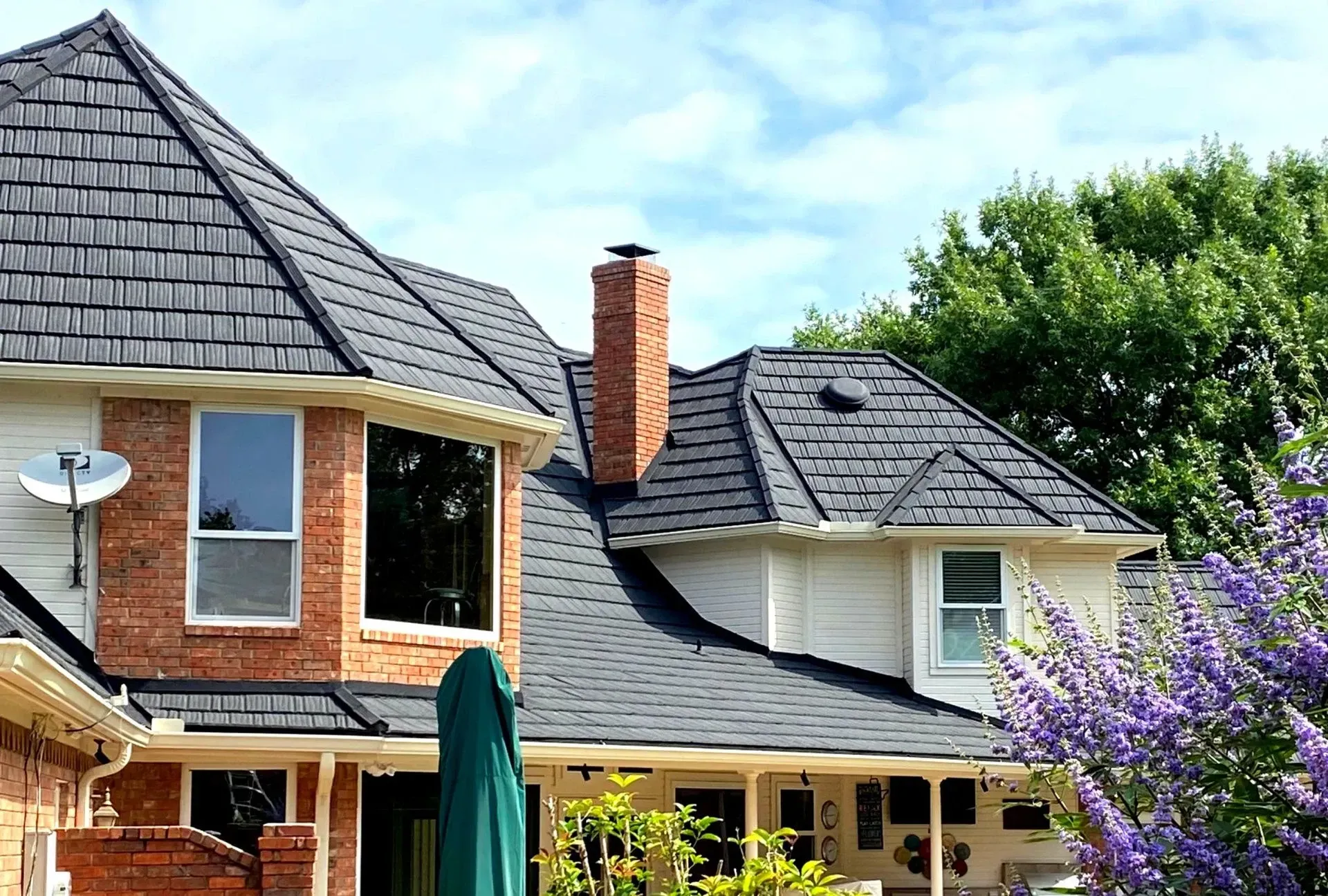 A roof with a vent on it and a building in the background.
