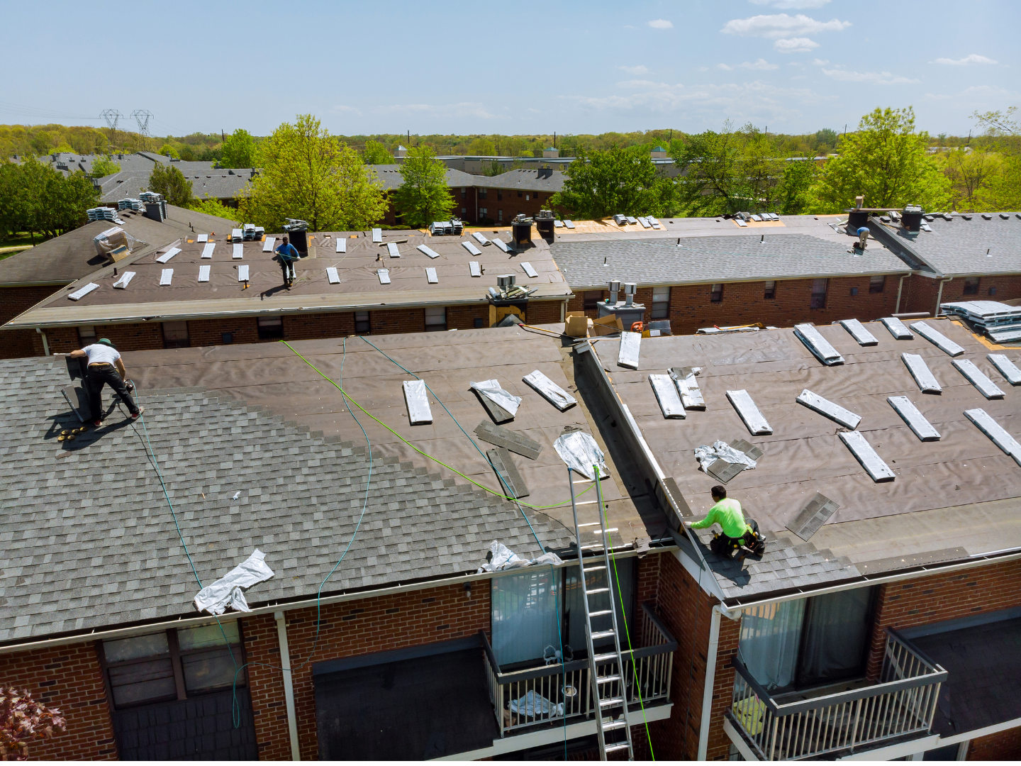 A roof with a vent on it and a building in the background.